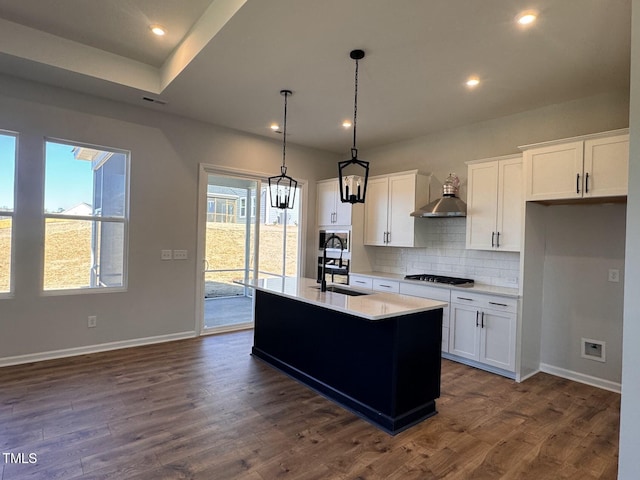 kitchen with dark wood-type flooring, sink, decorative light fixtures, a center island with sink, and white cabinets