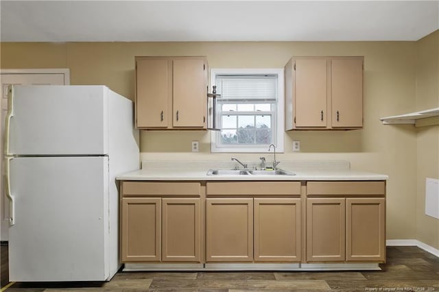 kitchen with white fridge, sink, light brown cabinets, and dark wood-type flooring