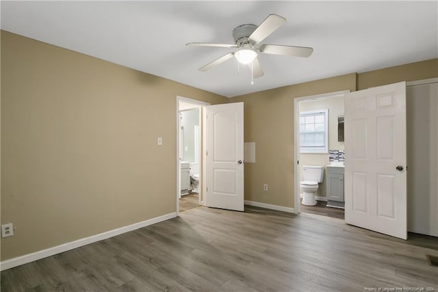 unfurnished bedroom with hardwood / wood-style floors, ceiling fan, and ensuite bath