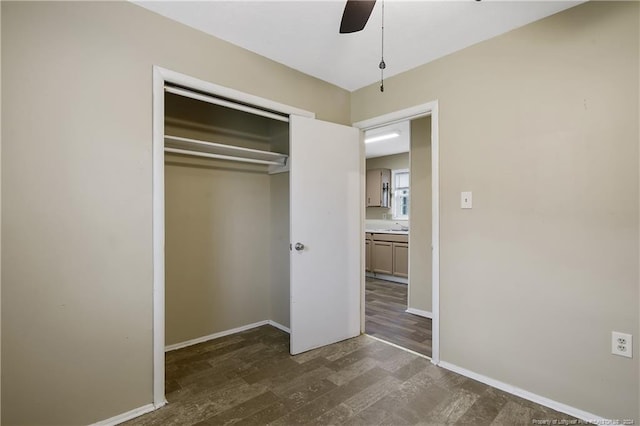 unfurnished bedroom featuring ceiling fan, sink, dark wood-type flooring, and a closet