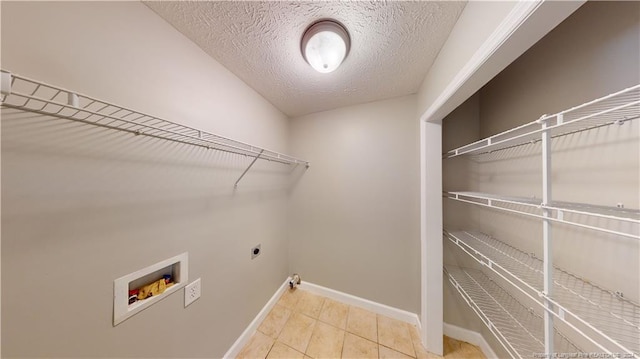 laundry room with hookup for an electric dryer, washer hookup, a textured ceiling, and light tile patterned floors