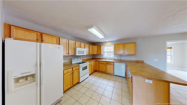 kitchen with white appliances, sink, a textured ceiling, light tile patterned flooring, and kitchen peninsula