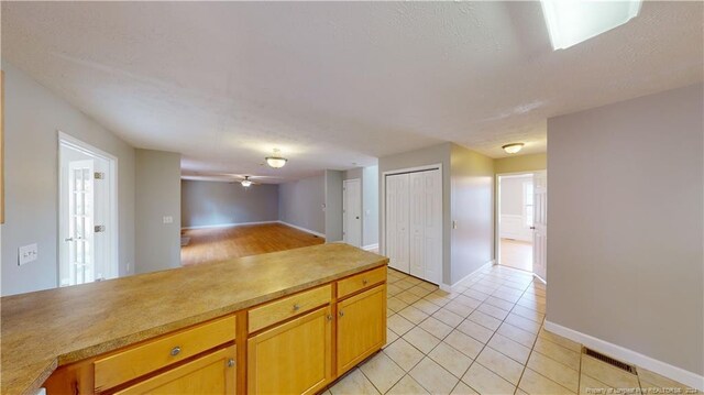 kitchen with ceiling fan, light tile patterned floors, and a textured ceiling