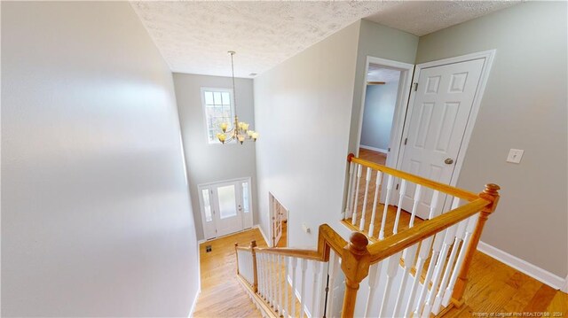 stairway with a chandelier, a textured ceiling, and hardwood / wood-style flooring