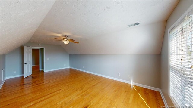 additional living space featuring a textured ceiling, ceiling fan, lofted ceiling, and hardwood / wood-style flooring