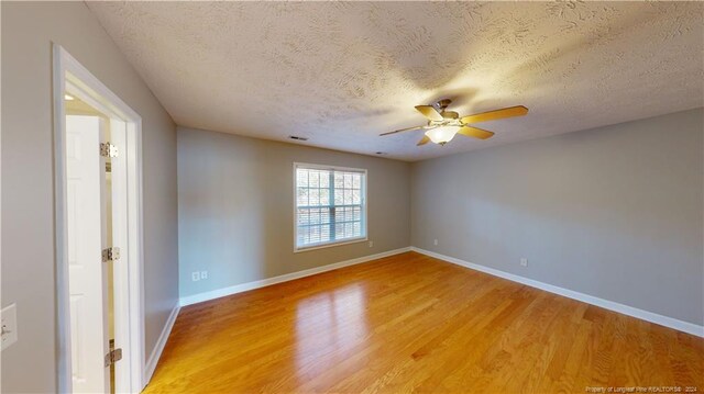 empty room with ceiling fan, wood-type flooring, and a textured ceiling