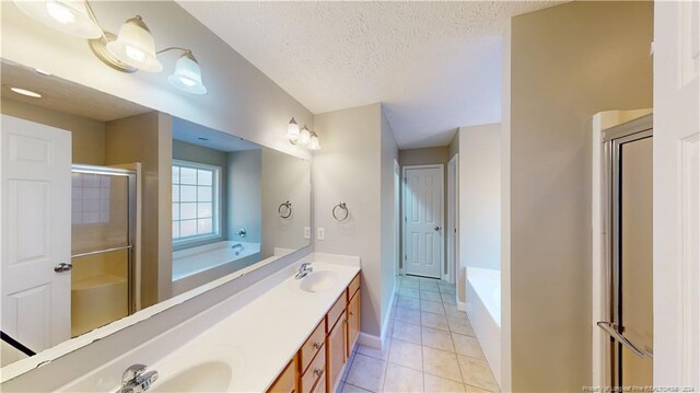 bathroom with tile patterned floors, separate shower and tub, vanity, and a textured ceiling