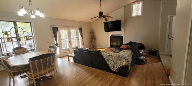 living room featuring ceiling fan with notable chandelier, wood-type flooring, lofted ceiling, and french doors