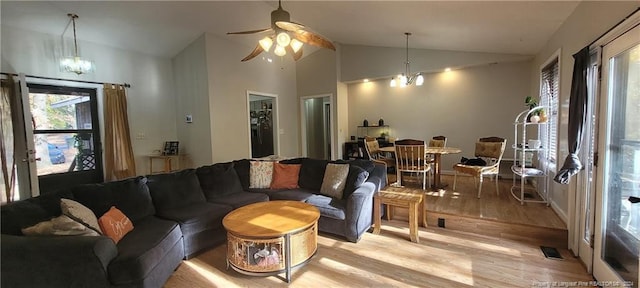 living room with light hardwood / wood-style flooring, ceiling fan with notable chandelier, and vaulted ceiling