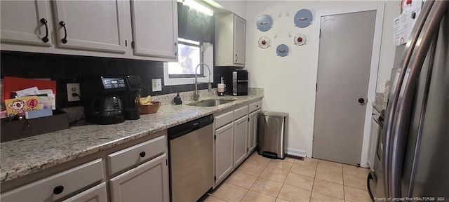 kitchen featuring decorative backsplash, appliances with stainless steel finishes, light stone countertops, sink, and light tile patterned floors