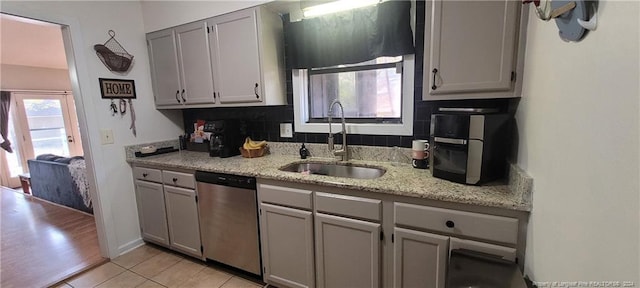 kitchen featuring gray cabinetry, sink, tasteful backsplash, stainless steel dishwasher, and light wood-type flooring