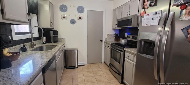 kitchen featuring light stone counters, sink, light tile patterned floors, and appliances with stainless steel finishes