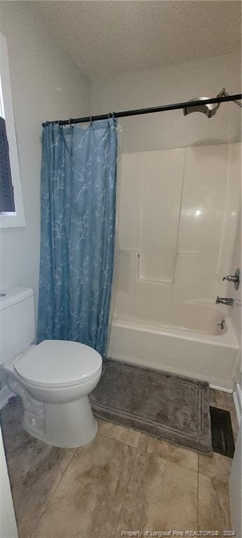 bathroom with shower / tub combo with curtain, tile patterned flooring, a textured ceiling, and toilet