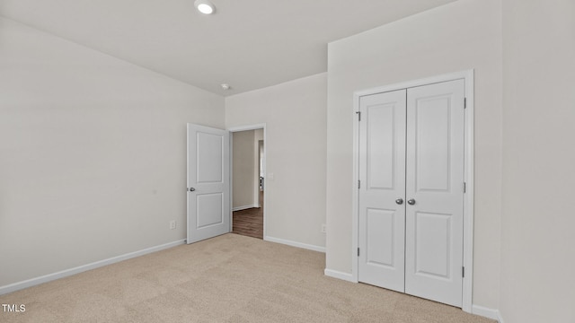 unfurnished bedroom with light carpet and a closet