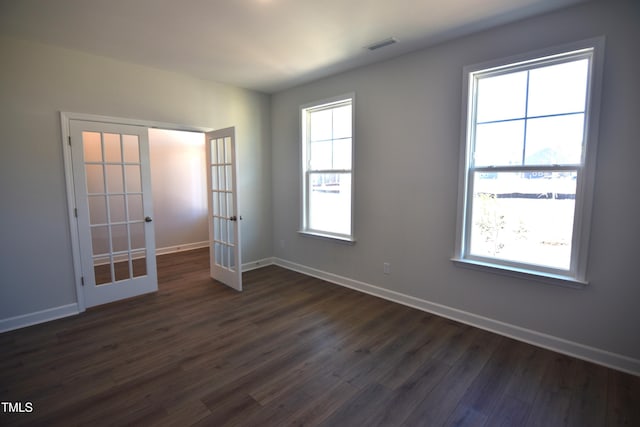 unfurnished room featuring dark wood-type flooring, french doors, visible vents, and baseboards