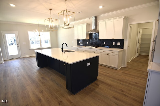 kitchen with stainless steel gas cooktop, wall chimney exhaust hood, ornamental molding, and a sink