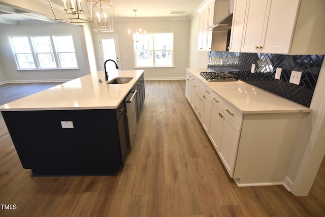 kitchen featuring light countertops, backsplash, appliances with stainless steel finishes, a sink, and wood finished floors