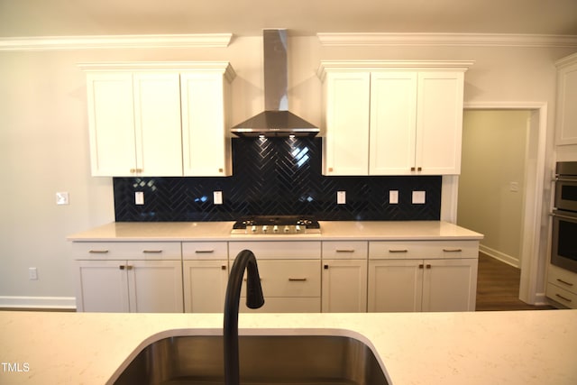 kitchen featuring stainless steel gas cooktop, a sink, ornamental molding, backsplash, and wall chimney exhaust hood