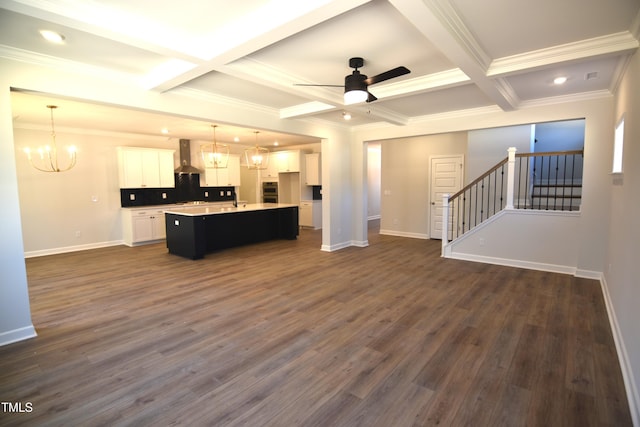 kitchen with open floor plan, white cabinets, wall chimney range hood, and ceiling fan with notable chandelier