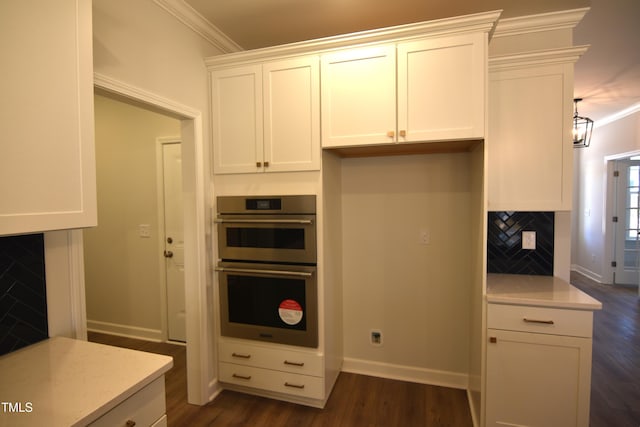 kitchen featuring ornamental molding, stainless steel double oven, dark wood finished floors, and tasteful backsplash