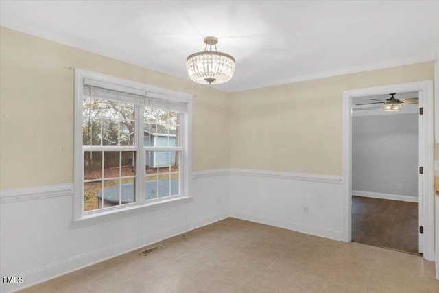 empty room featuring ceiling fan with notable chandelier and crown molding