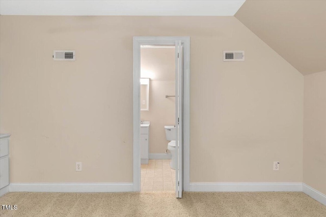 unfurnished bedroom featuring light colored carpet, connected bathroom, and vaulted ceiling