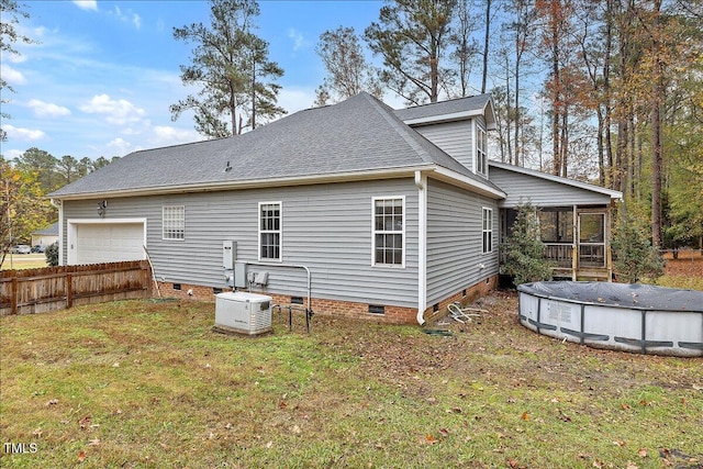 rear view of property with a yard, a garage, a covered pool, and a sunroom