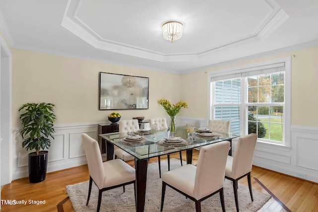 dining room featuring a tray ceiling, light hardwood / wood-style flooring, and ornamental molding