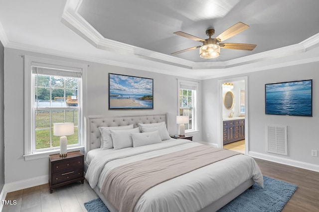 bedroom with ensuite bathroom, multiple windows, and ceiling fan