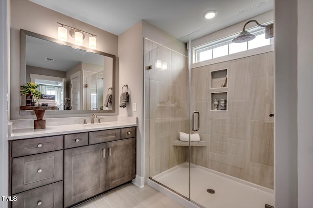 bathroom with a shower with door, vanity, and tile patterned floors