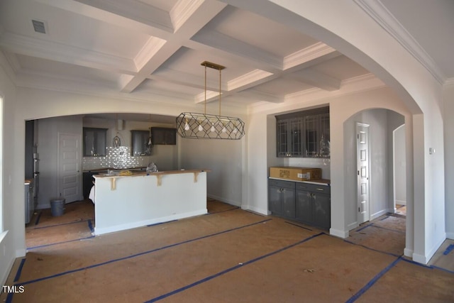 kitchen featuring coffered ceiling, a breakfast bar area, hanging light fixtures, beamed ceiling, and decorative backsplash