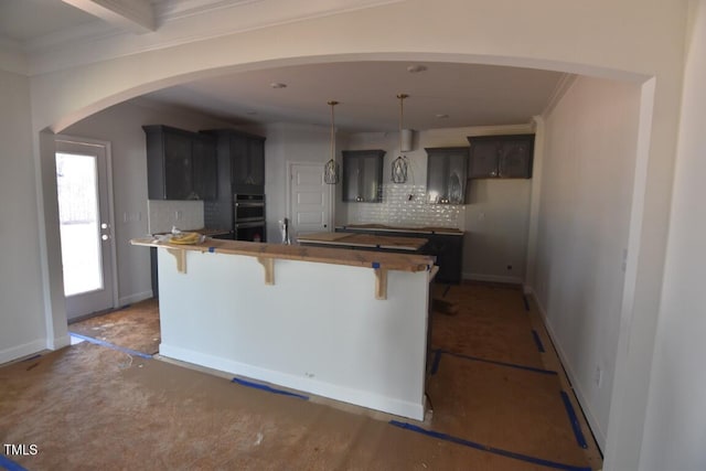 kitchen featuring hanging light fixtures, tasteful backsplash, double oven, a kitchen breakfast bar, and sink