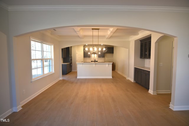 interior space featuring baseboards, coffered ceiling, wood finished floors, an inviting chandelier, and backsplash