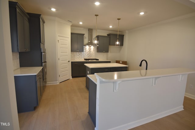 kitchen with wall chimney range hood, gas stovetop, a center island with sink, and light wood-style flooring