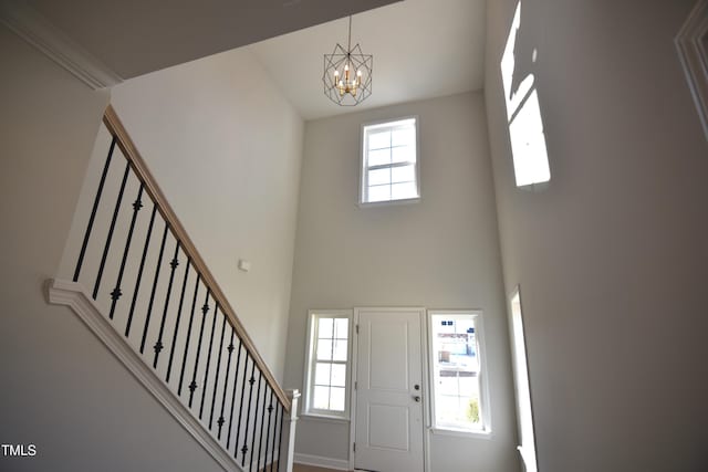 entryway with a chandelier, stairway, a towering ceiling, and a healthy amount of sunlight