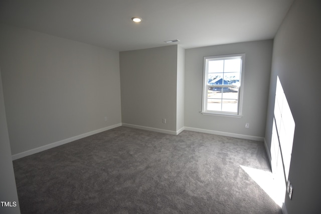 spare room featuring carpet floors, visible vents, and baseboards