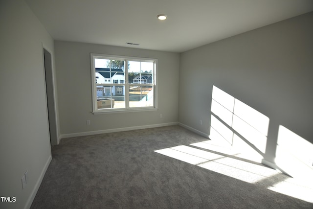 empty room with carpet, visible vents, and baseboards