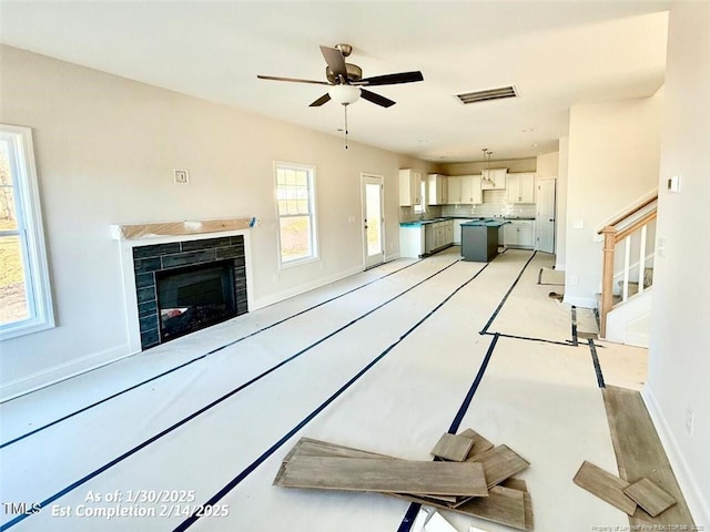 unfurnished living room featuring ceiling fan and a healthy amount of sunlight