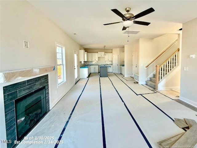 unfurnished living room featuring ceiling fan, a fireplace, and sink