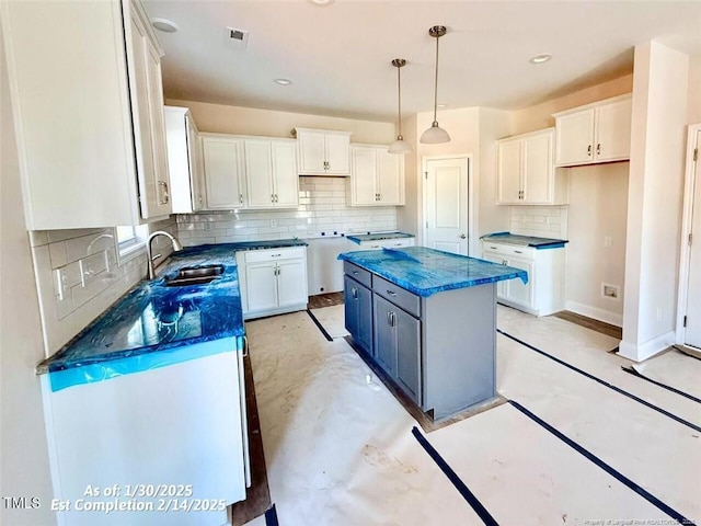 kitchen featuring pendant lighting, white cabinetry, sink, decorative backsplash, and a center island