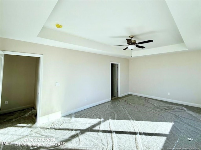 spare room featuring ceiling fan, a tray ceiling, and carpet