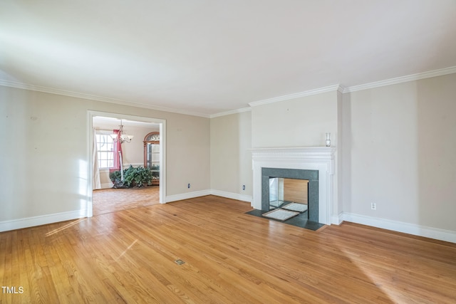 unfurnished living room with crown molding, light hardwood / wood-style floors, and an inviting chandelier