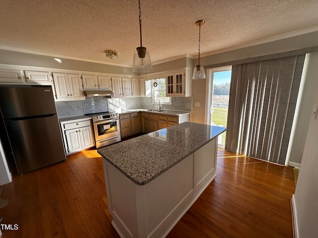 kitchen with white cabinets, stainless steel appliances, decorative light fixtures, and hardwood / wood-style flooring