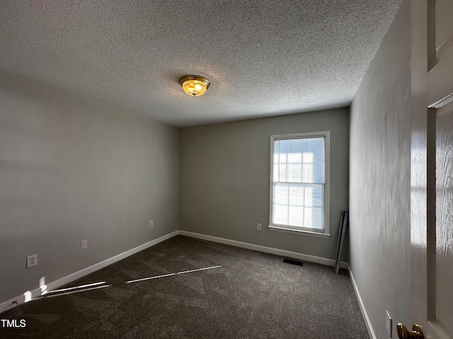 spare room with a textured ceiling and dark carpet