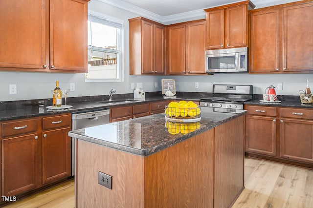 kitchen featuring ornamental molding, stainless steel appliances, sink, a center island, and light hardwood / wood-style floors