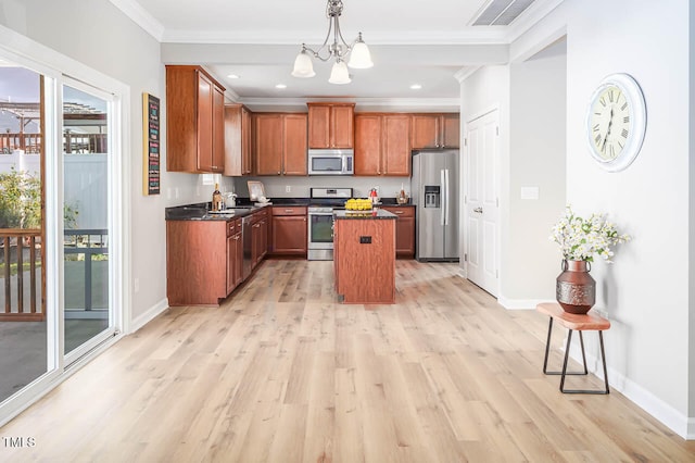 kitchen with a notable chandelier, appliances with stainless steel finishes, decorative light fixtures, a kitchen island, and light wood-type flooring