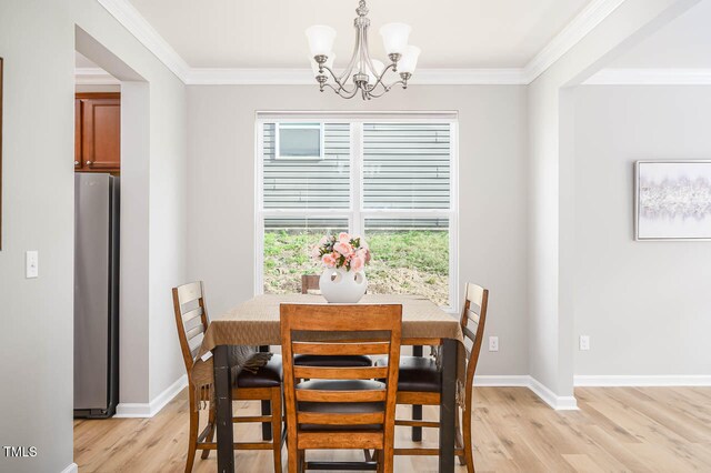 dining space with a chandelier, ornamental molding, and light hardwood / wood-style flooring