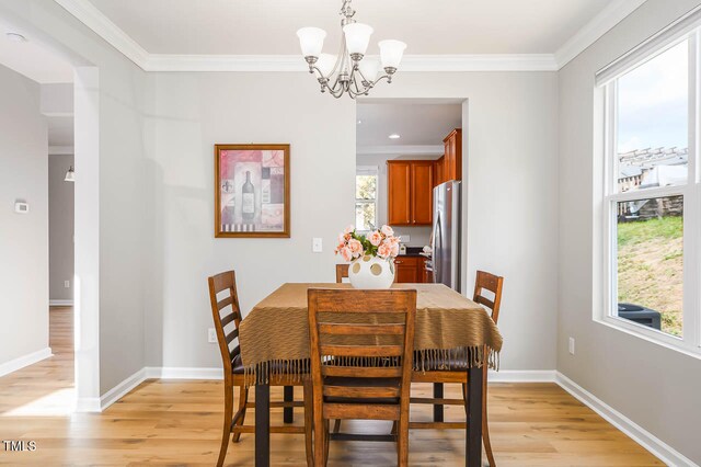 dining space with a chandelier, light hardwood / wood-style flooring, plenty of natural light, and crown molding