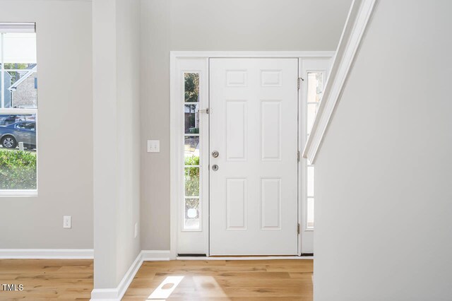 entryway featuring plenty of natural light, ornamental molding, and light hardwood / wood-style flooring