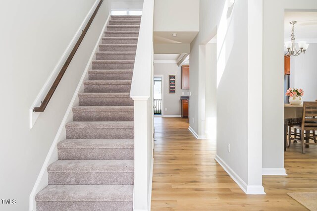 stairway with hardwood / wood-style flooring, a notable chandelier, and crown molding